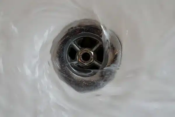 Water swirling down a metal drain, creating a whirlpool effect.
