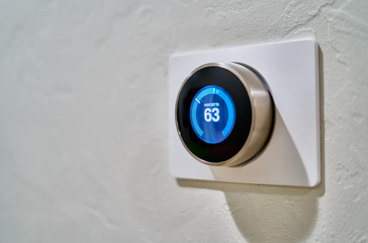 A digital thermostat set to 63 degrees Fahrenheit is mounted on a textured white wall.