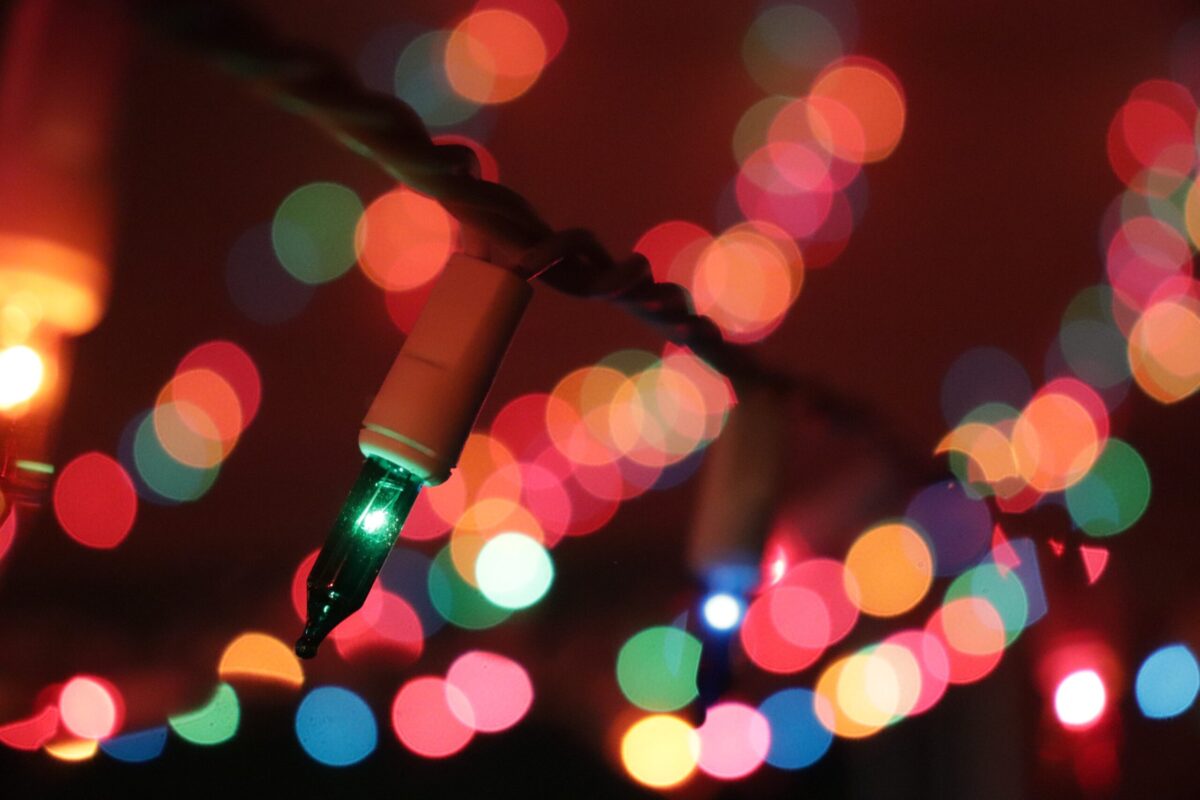 Close-up of colorful string lights with a bokeh effect in the background, featuring red, green, and blue hues softly glowing in a dark setting.