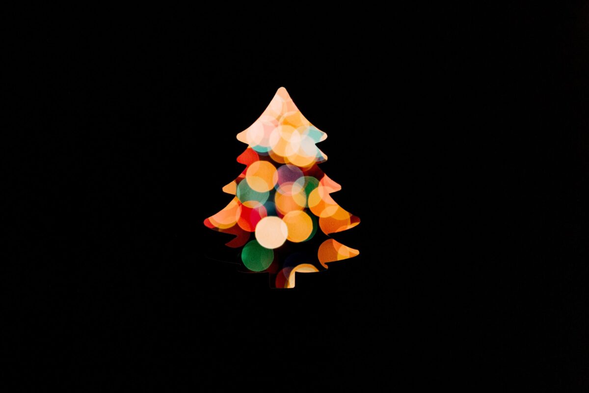 A Christmas tree silhouette filled with colorful, blurred lights against a black background.