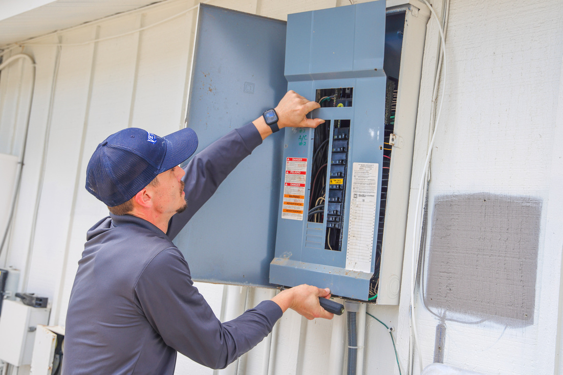A man holding a tool in front of a grey box.