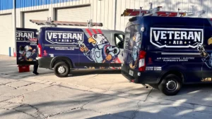 Two service vans labeled "Veteran Air" with eagle mascots are parked outside a building. A person stands near one van.
