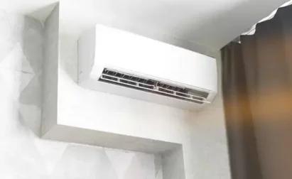 A mini-split air conditioner is neatly installed above a curtain in the corner of the room. Its strategic placement ensures optimal cooling, making repair or maintenance easy and efficient.