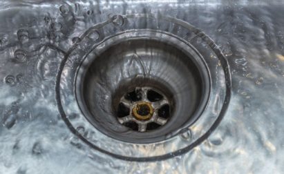 Water swirling down a stainless steel sink drain.