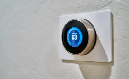 A digital thermostat set to 63 degrees Fahrenheit is mounted on a textured white wall.