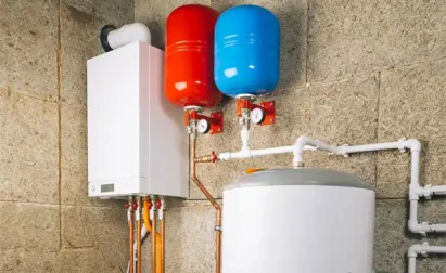The heating system, featuring a white boiler connected to red and blue expansion tanks and a cylindrical storage tank, exemplifies efficient water heater installation when mounted on the textured wall.