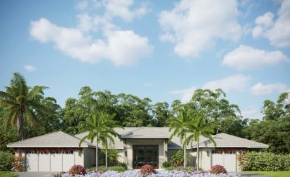 Single-story house with a flat roof, two garages, palm trees, and landscaped garden with colorful flowers in front, set against a backdrop of trees and a partly cloudy sky.
