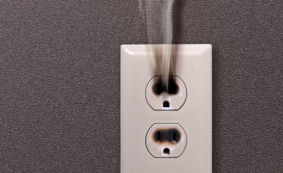 Electrical outlet on a wall emitting smoke, indicating a potential fire hazard or overheating issue.