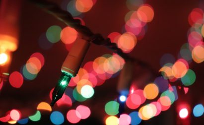 Close-up of colorful string lights with a bokeh effect in the background, featuring red, green, and blue hues softly glowing in a dark setting.