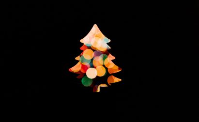 A Christmas tree silhouette filled with colorful, blurred lights against a black background.